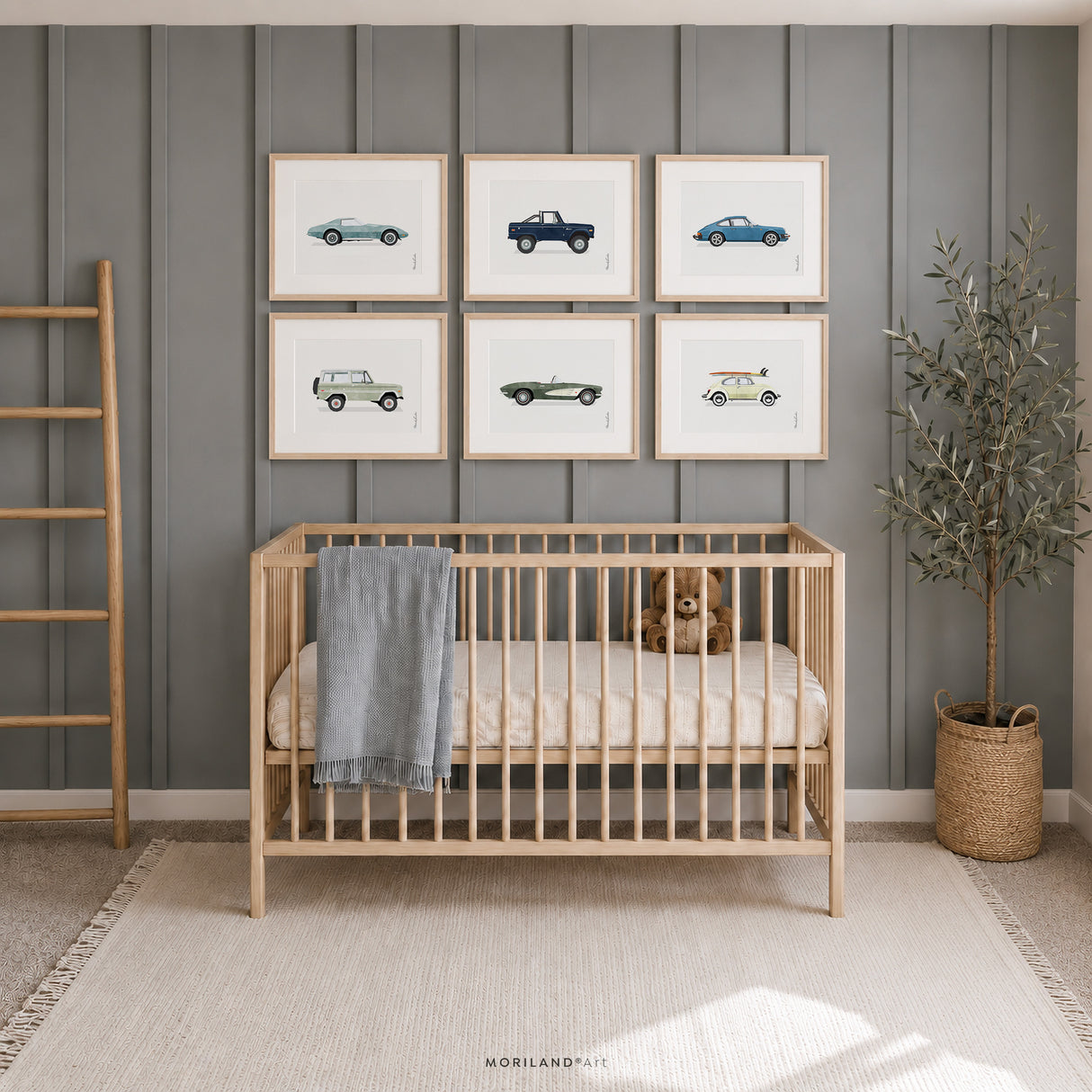 Set of six classic vehicle prints in light wood frames above a natural wood crib in a soft blue baby boy nursery with a teddy bear and woven décor.