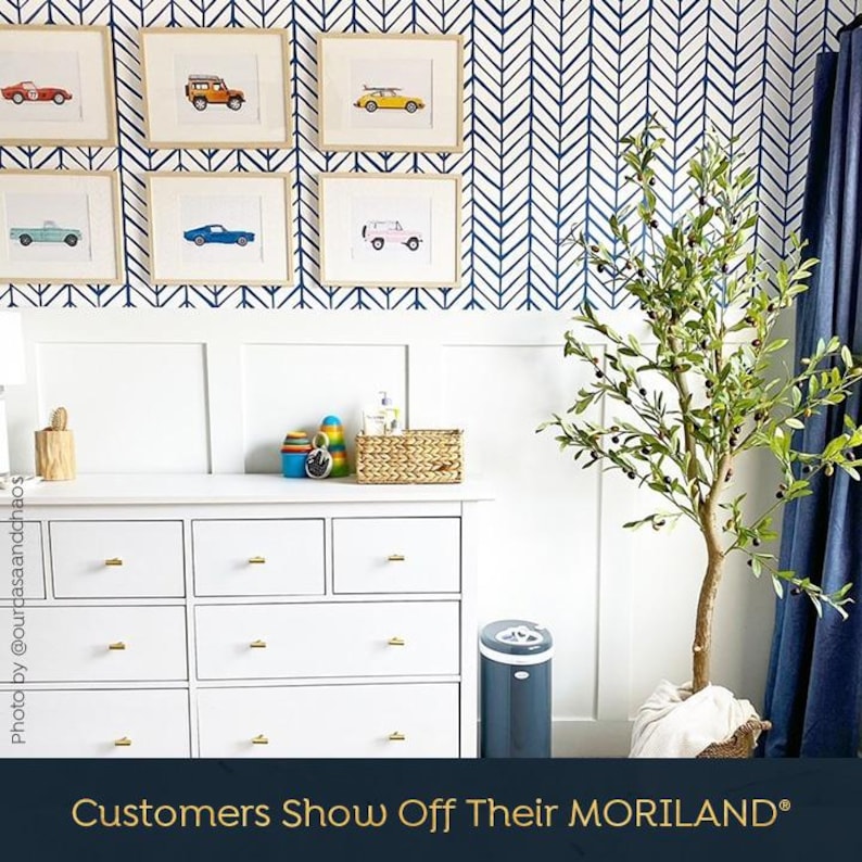 Customer nursery with framed MORILAND vintage car prints above a white dresser