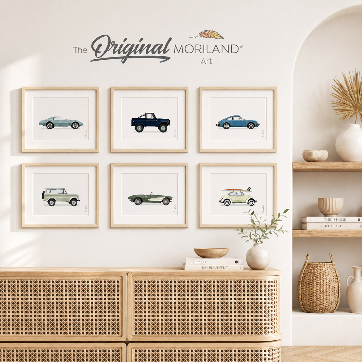 Set of six MORILAND classic car fine art paper prints in light wood frames, displayed in a bright neutral living room above a cane cabinet.