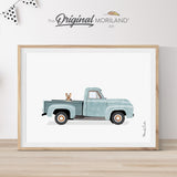 Modern heritage watercolor style illustration of a Yorkshire Terrier dog sitting in the bed of a pale blue vintage classic pickup truck, displayed in a light wood frame for a nursery or dog lover gift by MORILAND.