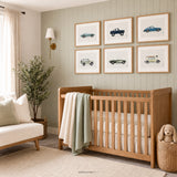 Set of six classic vehicle prints in light wood frames above a natural wood crib in a soft blue baby boy nursery with a teddy bear and woven décor.