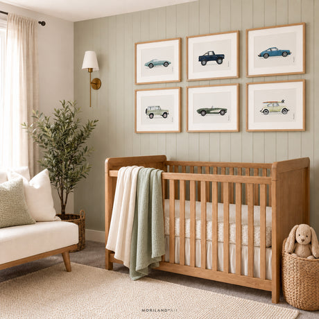 Set of six classic vehicle prints in light wood frames above a natural wood crib in a soft blue baby boy nursery with a teddy bear and woven décor.