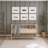 Set of six classic vehicle prints in light wood frames above a natural wood crib in a soft blue baby boy nursery with a teddy bear and woven décor.