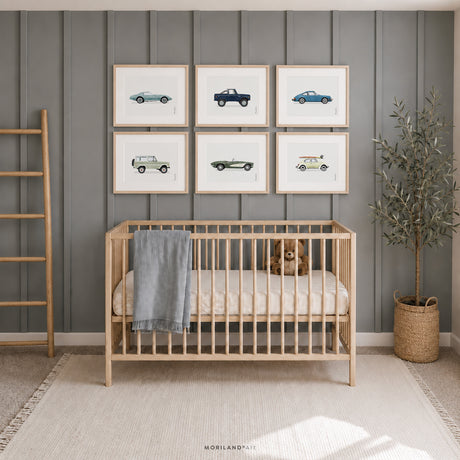 Set of six classic vehicle prints in light wood frames above a natural wood crib in a soft blue baby boy nursery with a teddy bear and woven décor.